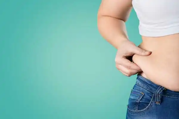 Image of woman pinching her love handles to show weight gain Cumbernauld
